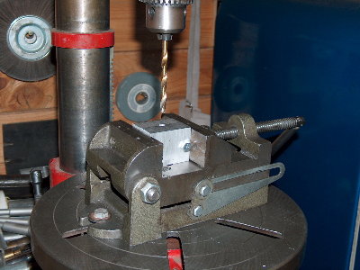 Bolt the vise onto the drill press. Using the hole you just drilled, carefully line up with the drill bit as you did before. Snug everything down. (Watch out for cheap drill vises, they tilt the work when you tighten them.) Double check alignment.