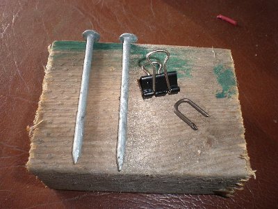 To build the holder you need a lump of wood, two nails, a document clip, and a way of attaching the document clip.