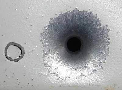 entry hole with a 0.22 pellet at 10x, note the pellet skirt to the left of the hole which separated on impact