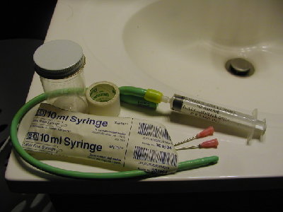 Hazardous materials include an expired date catheter, a specimen sample jar, hypodermic needles, single use syringes, and the contaminated left over roll of tape.