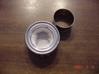 Take the inner can out and stuff the inside with the cotton.Put the can back in and push it down to the bottom.If any cotton sticks out into the middle while going down just use your finger to push it back into the inner space.